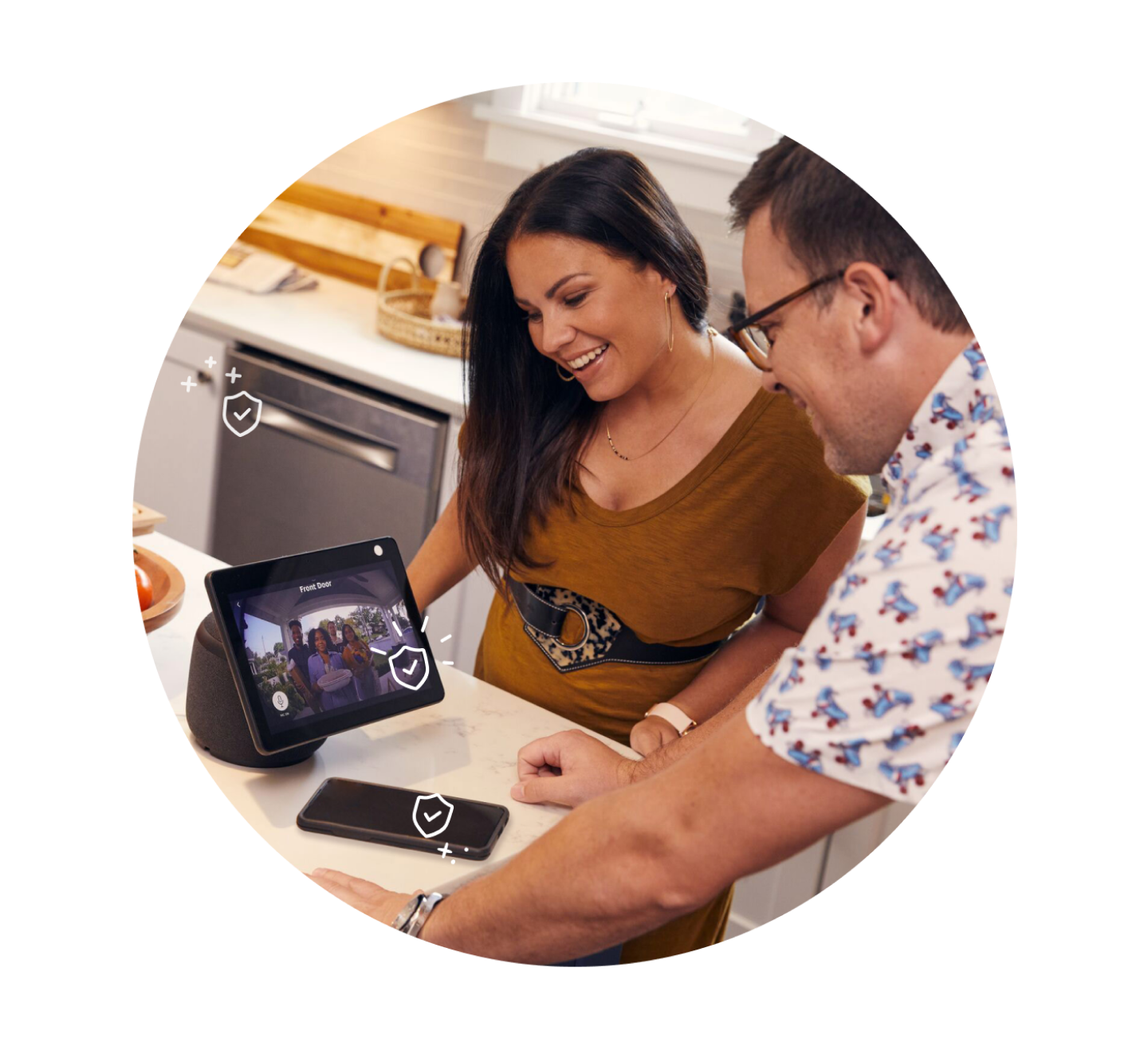 Two people looking at the Google Nest Hub in kitchen with a mobile phone and appliances