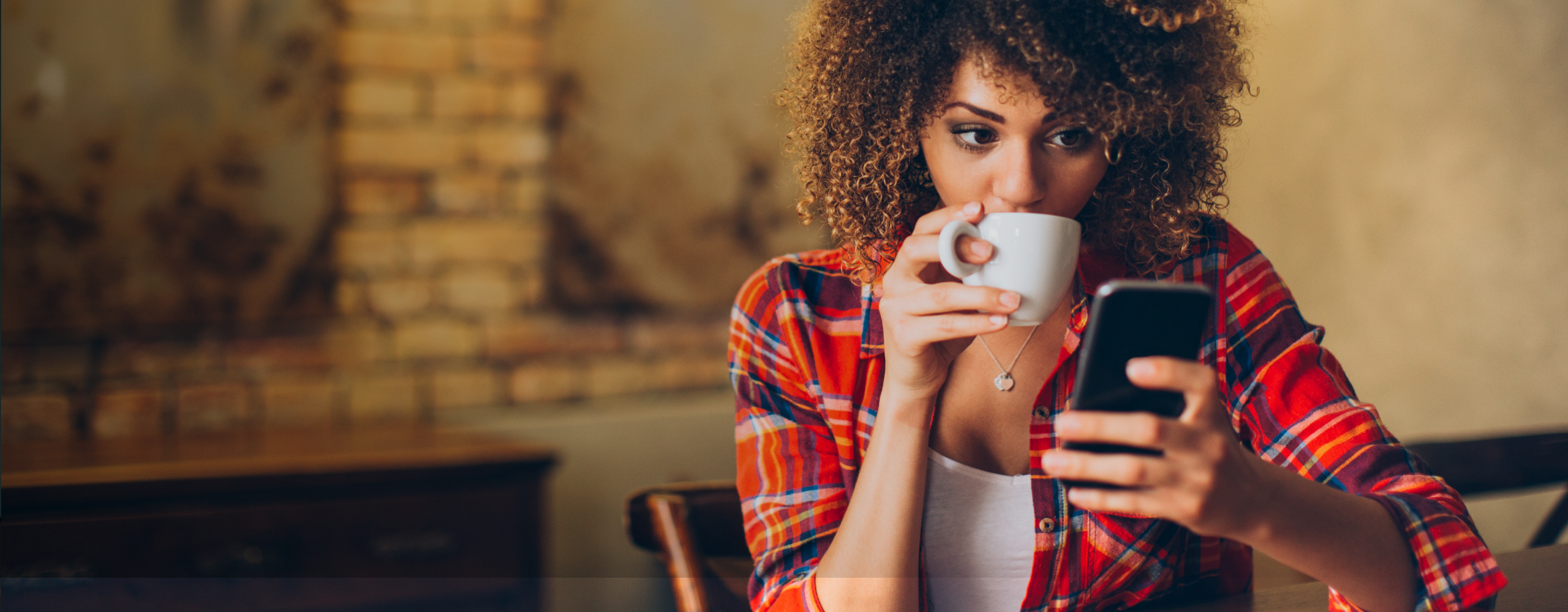 Woman drinking coffee looking at cell phone